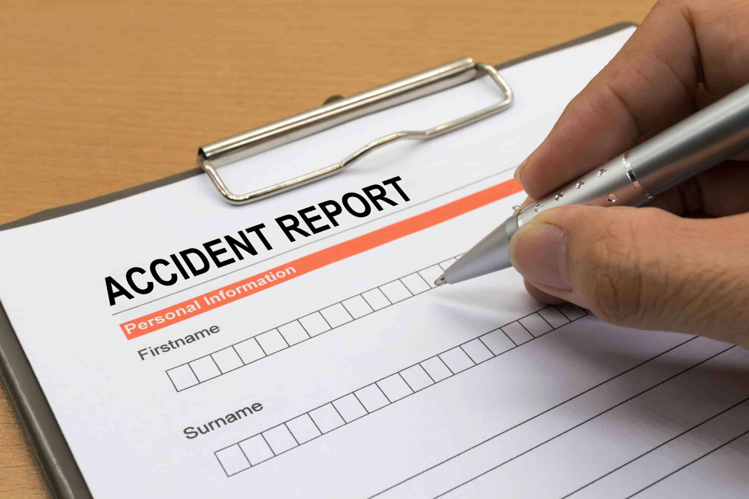 Person filling out an accident report form on a clipboard—an essential first step in knowing what to do after an injury at work in New York.